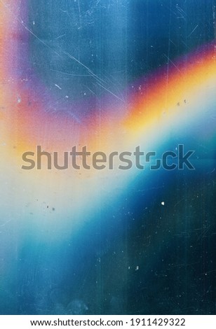 Lens flare background. Dust scratches texture. Blue distressed faded stained screen with smeared dirt noise blur colorful orange rainbow glow defect. Royalty-Free Stock Photo #1911429322