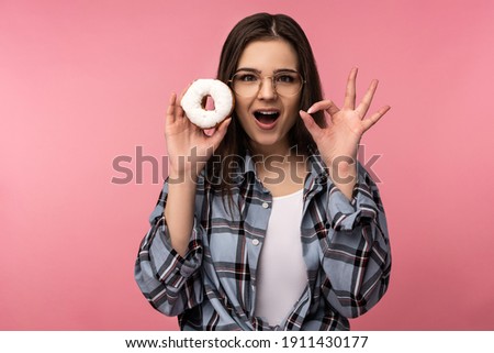 Photo of attractive lady holds donuts smile, happy shows OK, wear casual checkered shirt white undershirt isolated pink color background
