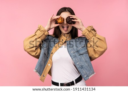 Photo of attractive lady covered eyes with muffins fun, wear casual jeans jacket white undershirt isolated pink color background