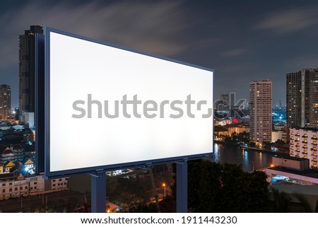 Blank white road billboard with Bangkok cityscape background at night time. Street advertising poster, mock up, 3D rendering. Side view. The concept of marketing communication to sell idea.