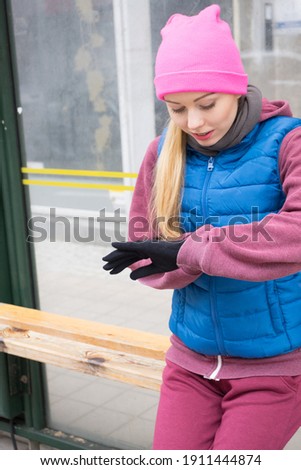 Outdoor sport exercises, sporty outfit ideas. Young woman wearing warm sportswear waiting for bus