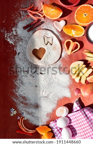 a board sprinkled with flour, with a dough on which there is a hole in the shape of a heart. Preparation for baking.  Valentine's Day background. Top view