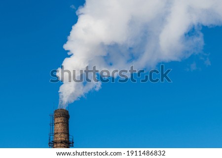 Gray smoke smokes through the yellow brick chimney.