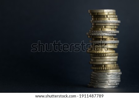 Euro coins of different denominations are messily stacked on a black blurred background with space for text Royalty-Free Stock Photo #1911487789