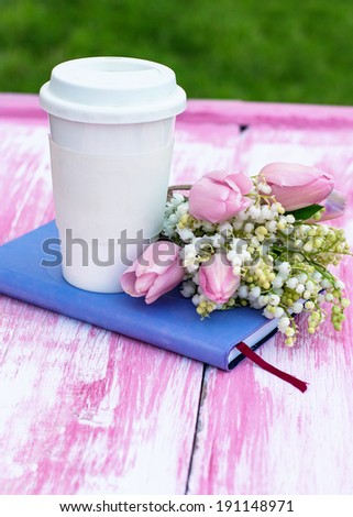 diary, a glass of coffee and  lilies of valley and tulips on the table