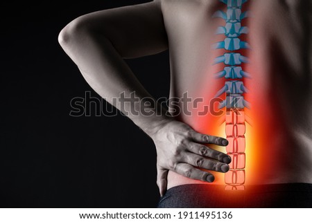 Pain in the spine, man with backache on black background, intervertebral hernia or disc injury concept Royalty-Free Stock Photo #1911495136