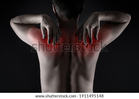 Shoulder blades pain, man with backache on black background, painful area highlighted in red Royalty-Free Stock Photo #1911495148
