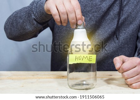 lamp in savings jar on gray background