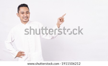 Asian man wearing moslem clothes pointing blank screen  isolated white background