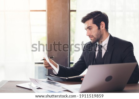 Side view of young businessman using computer while sitting at desk in home office
