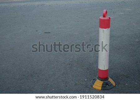 traffic cone, with white and orange stripes on gray asphalt, Drive safety and constructions concept.