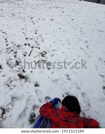 boy child on sled on hill with snow in winter