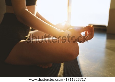 Young girl relaxing in yoga position in front of a bright window