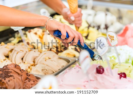 Young saleswoman in an ice cream parlor takes a scoop of ice cream Royalty-Free Stock Photo #191152709