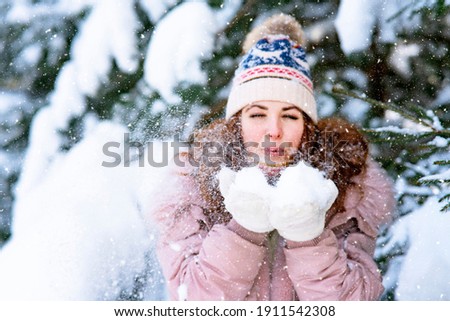 Happy woman on the background of the forest, snow falls on the girl, the female smiles in winter.