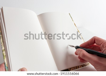 Nice notebook to write poetry on a white background and a metal pen with India ink and empty space to write