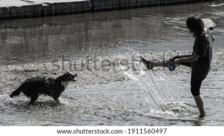The third photo from pentaptych "Swiss Contour". On the shallows of the river in the park of Lugano, a young man plays with a dog. Dynamics, flying spray, contour lighting.