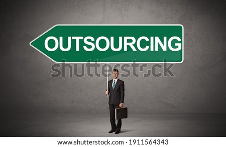 Young business person in casual holding road sign with OUTSOURCING inscription, new business direction concept