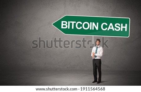 Young business person in casual holding road sign with BITCOIN CASH inscription, new business direction concept