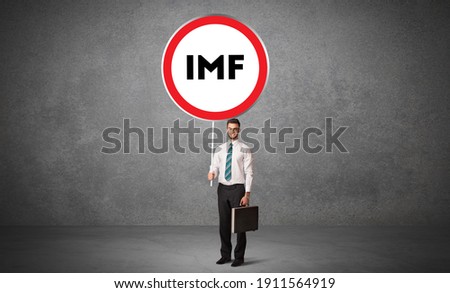 Young business person holdig traffic sign with IMF abbreviation, technology solution concept
