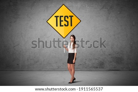 Young business person holding road sign with TEST inscription, new rules concept