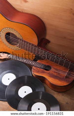 Vintage acoustic guitars and vinyl records on a wooden background