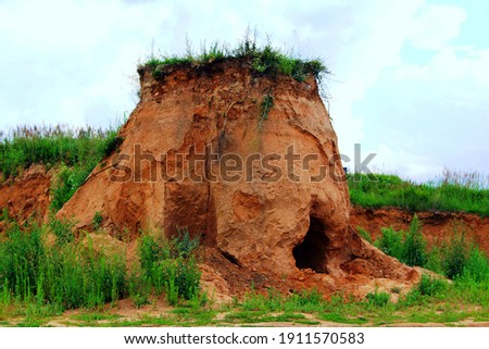 A large brown clay cave against the backdrop of a cloudy cloudy sky.