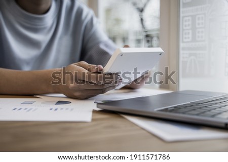 Financial or accounting professionals use a laptop to analyze the company's revenue-expenses graph to prepare for presentation to the chief executive and partner, businesswomen working in the room.