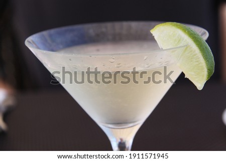 frosted cocktail glass with pale cocktail drink and lime wedge as garnish on the glass