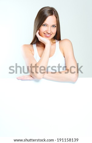 smiling happy woman standing and holding big blank paper.