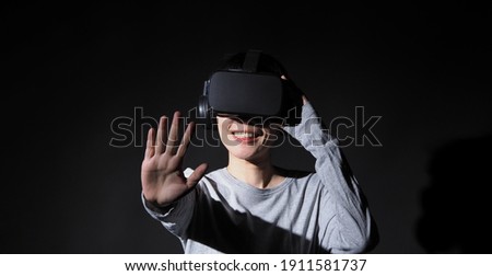 Girl with hands up wearing the VR headset goggles. Asian woman in glasses of virtual reality. The concept of futuristic. Digital VR glasses. Woman getting cyber experience using modern black color VR