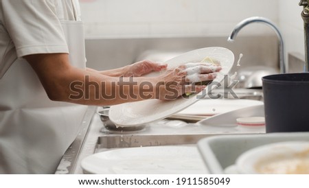 Man washing dish on sink at restaurant Royalty-Free Stock Photo #1911585049