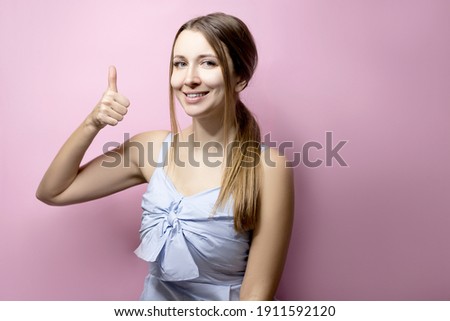 Portrait of beautiful emotional woman isolated on a pink background. Like by sign language.
