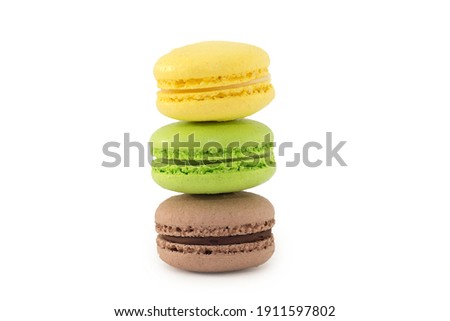 three multi-colored cookies stand on top of each other on a white background. Macaron. Yellow, green, brown. Close-up, horizontal photo