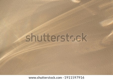 Background with shining lines of natural light on a sand color textured wall.Minimal summer concept with shadows on the wall.Creative copyspace for overlay on product presentation,backdrop and mockup.