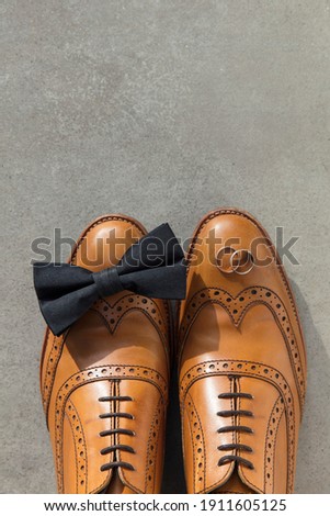 Wedding rings and bow tie on a pair of leather shoes Royalty-Free Stock Photo #1911605125
