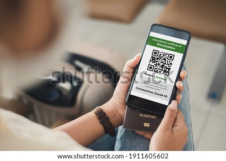 Traveler shows health passport of vaccination certification on phone at airport, to certicy that have been vaccinated of coronavirus covid-19 Royalty-Free Stock Photo #1911605602