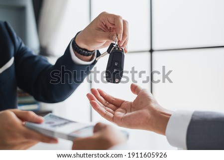 Closeup hand giving a car key and money for loan credit financial, lease and rental concept Royalty-Free Stock Photo #1911605926