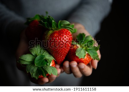 small hands holding a fresh strawberry - horizontally