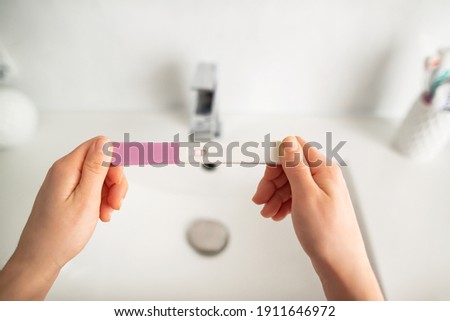Young woman checking pregnancy test kit in bathroom. 
