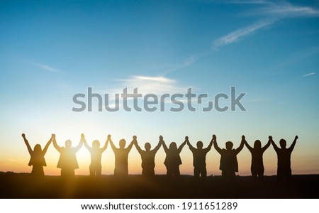 Silhouette of group happy business team making high hands over head in sunset sky background for business teamwork concept. Royalty-Free Stock Photo #1911651289
