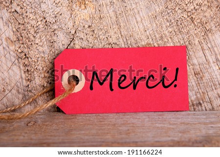 A Red Tag on Wood with the French Word Merci which means Thanks