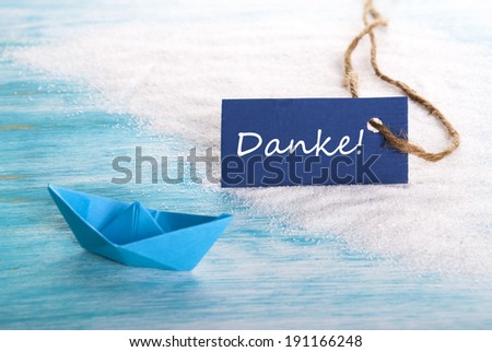A Blue Tag with the German Word Danke which means Thanks, at a Beach with a Boat