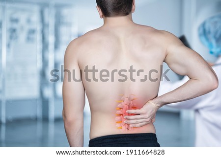 The patient stands and holds on to the spine on a blurred background. Royalty-Free Stock Photo #1911664828