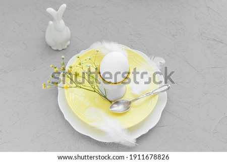 Happy easter breakfast or branch, egg on plate with decoration and gypsophila flower  and easter rabbit. Composition in Colors of the year 2021: ultimate gray and illuminating yellow.