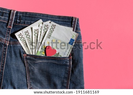 Money and heart in jeans pocket on light pink background with copy space. Euro banknotes and heart shape love symbol. Charity, donation, helpful concept. Isolated, top view, flat lay