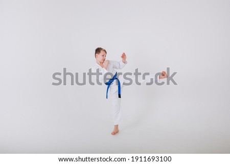 little boy in a white kimono practices punches on a white background with a place for text