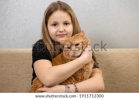 Attractive little girl with red fluffy cat on sofa in room