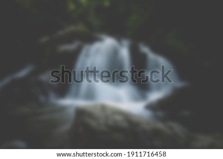Waterfall blurred unfocused background in forest. Dark color.