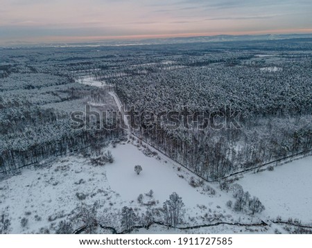 aerial view of snowy landscape with forest and meandering brook
